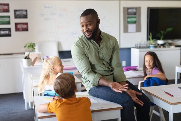 Caucasian Elementary Students Looking African American Young Male Teacher Teaching Stock Photo