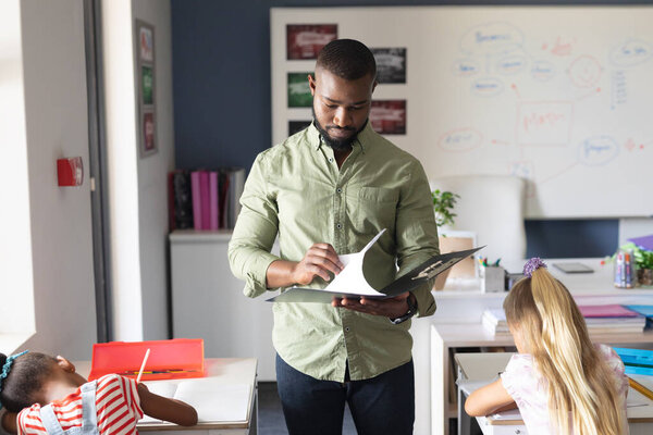 African American Young Male Teacher Reading File While Standing Multiracial Royalty Free Stock Images