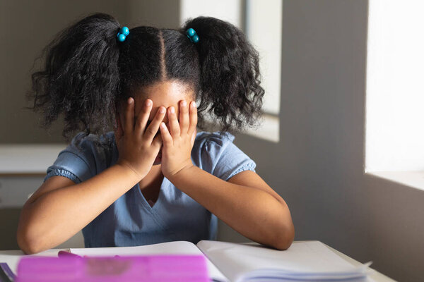 Sad Biracial Elementary Schoolgirl Hands Covering Face Sitting Desk Classroom Royalty Free Stock Images