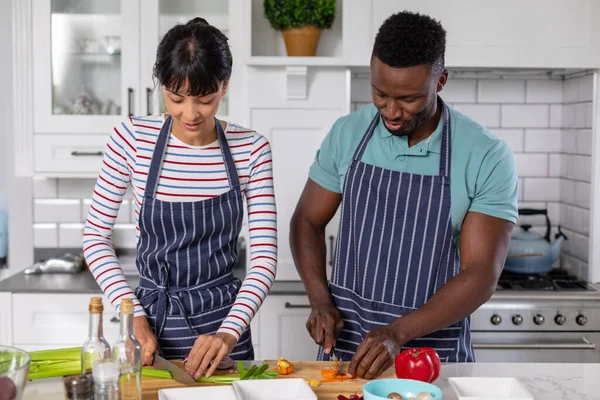 家庭のキッチンで一緒に料理をしながら 多人種の若いカップルが野菜を切り刻む 変わらないライフスタイルレジャー一緒に料理を — ストック写真