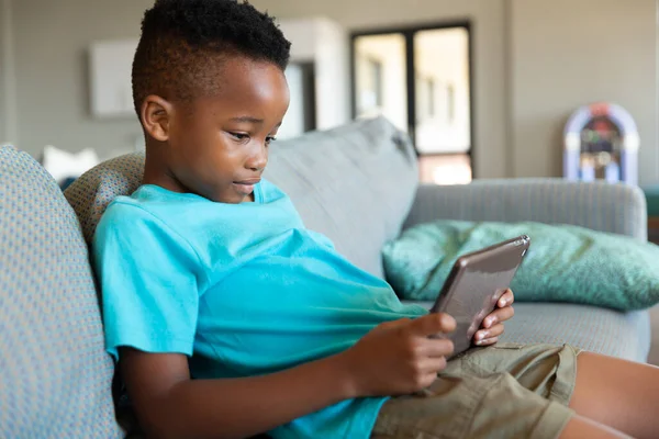 Niño Afroamericano Primaria Usando Tableta Digital Mientras Está Sentado Sofá —  Fotos de Stock