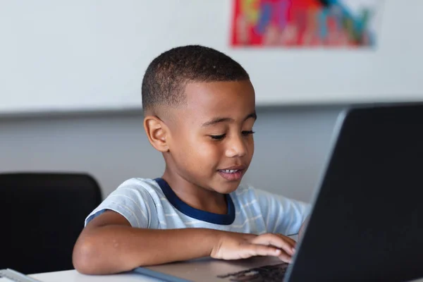 坐在课桌前 用笔记本电脑对着非洲裔美国小学生笑 无线技术 学习和学校概念 — 图库照片