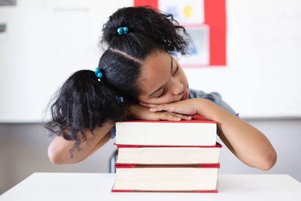 教室の机の上に置かれた本に寄りかかっている生粋の小学生 変化のない教育学習疲れリラックス保護学校の概念 — ストック写真