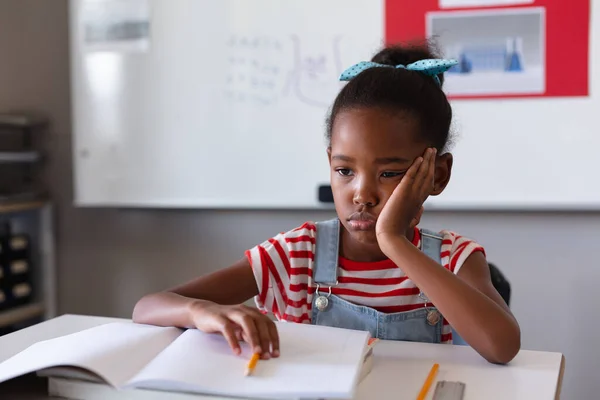 アフリカ系アメリカ人の悲しい女の子が頬に手を置き 教室の机の上に座っている本 変化のない教育学習学習学習学校の概念 — ストック写真
