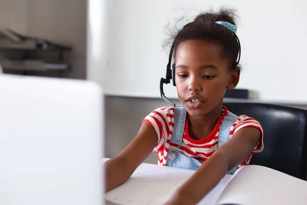 African American Elementary Schoolgirl Wearing Headphones While Using Laptop Desk — Stock Photo, Image