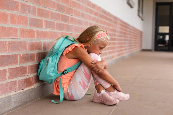 学校の床に座っている間悲しい白人の小学生の抱擁膝の完全な長さ 変化のない教育悲しみうつ病孤独学校の概念 — ストック写真