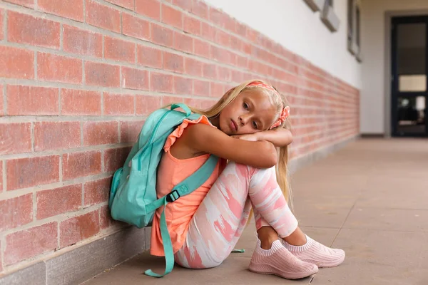 学校で床に座っている間 バックパックの抱擁膝を持つ悲しい白人小学生 変化のない教育悲しみうつ病孤独学校の概念 — ストック写真