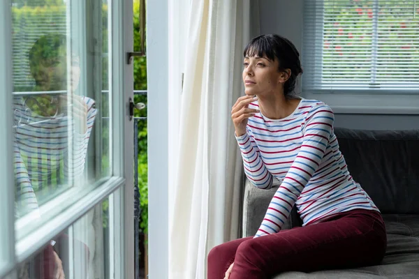 Düşünceli Beyaz Bir Kadın Evde Otururken Pencereden Dışarı Bakıyor Değiştirilmemiş — Stok fotoğraf