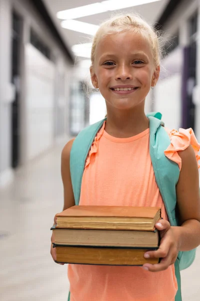 廊下に立ちながら本を持っている笑顔の白人小学生の肖像画 変化のない子供時代教育幸福学習学校の概念 — ストック写真