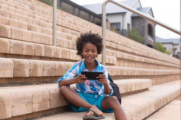 Gülümseyen Afro Amerikan Ilkokulu Okul Merdivenlerinde Otururken Akıllı Telefon Kullanıyor — Stok fotoğraf