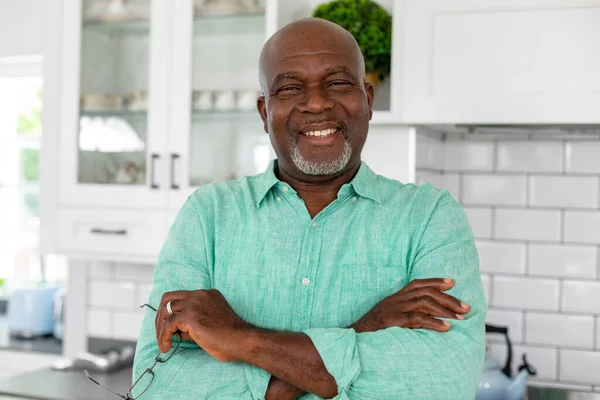アフリカ系アメリカ人の老人が腕を組んでキッチンに立っている姿が描かれている 変わらないライフスタイル退職国内生活 — ストック写真