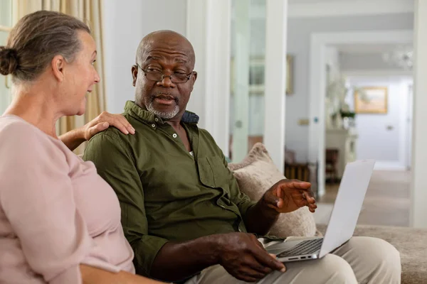 Senior Multiracial Couple Laptop Discussing While Sitting Sofa Home Unaltered — Stock Photo, Image