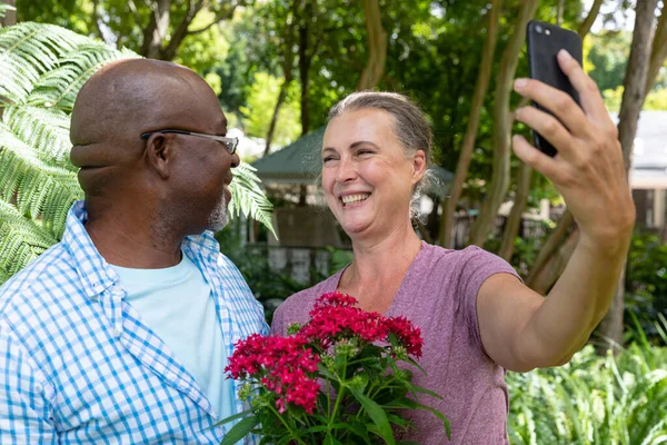 Feliz Pareja Ancianos Multirraciales Con Flores Tomando Selfie Través Del — Foto de Stock