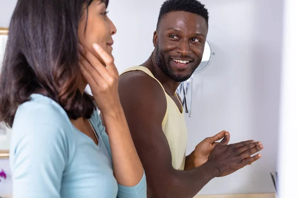 Smiling African American Man Looking Caucasian Girlfriend Applying Moisturizer Face — Stok fotoğraf