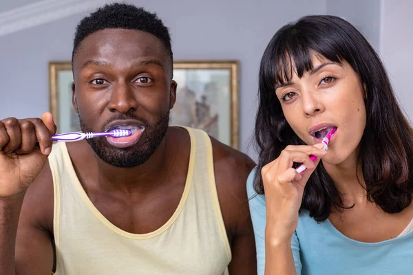 Portrait Multiracial Young Couple Brushing Teeth Bathroom Home Unaltered Lifestyle — стоковое фото