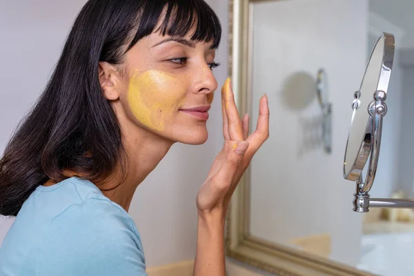 Vit Ung Kvinna Tittar Spegeln Och Applicera Ansiktsmask Badrummet Oförändrad — Stockfoto