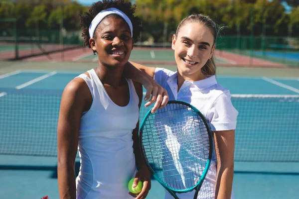 ラケットとボールがテニスコートに立っていると笑顔の多人種女性選手の肖像画 変更なしスポーツ競技テニスの概念 — ストック写真