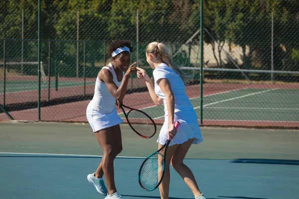 Glada Biracial Kvinnliga Tennisspelare Pekar Varandra Medan Spelar Domstol Solig — Stockfoto