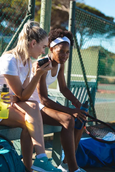 Thoughtful Female Biracial Tennis Players Sitting Bench Court Game Break — Zdjęcie stockowe