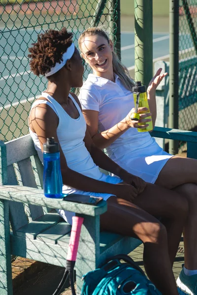 休憩中は裁判所のベンチに座りながら 多人種の若い女性テニス選手の笑顔 変更なしスポーツ競技テニスの概念 — ストック写真