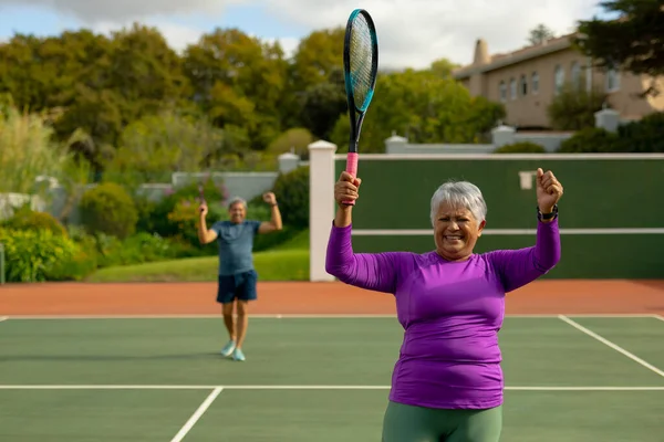 Happy Biracial Senior Woman Holding Racket Gesturing Tennis Court Man — Stockfoto