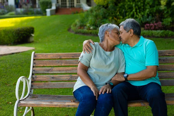 Romantic Biracial Senior Husband Kissing Senior Woman While Sitting Bench — Foto de Stock