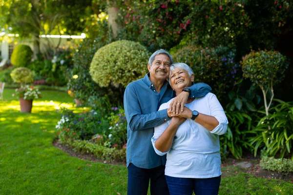 Smiling Biracial Senior Couple Embracing Looking While Standing Plants Park —  Fotos de Stock