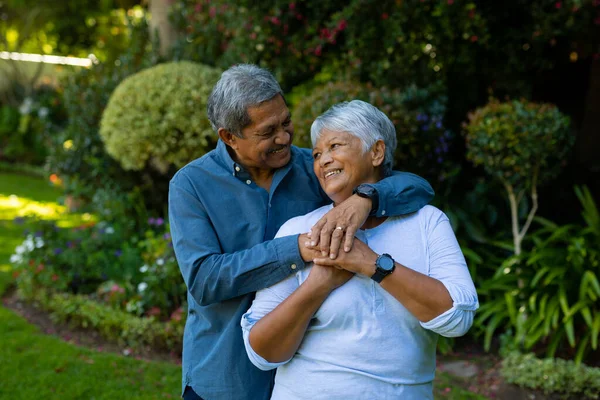 Smiling Biracial Senior Couple Embracing Holding Hands While Standing Plants — Foto de Stock