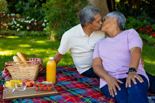 Biracial Senior Couple Kissing While Sitting Bread Fruits Juice Blanket — ストック写真