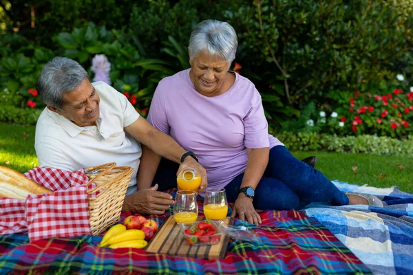 Biracial Homem Sênior Derramando Suco Vidro Enquanto Desfruta Piquenique Com — Fotografia de Stock