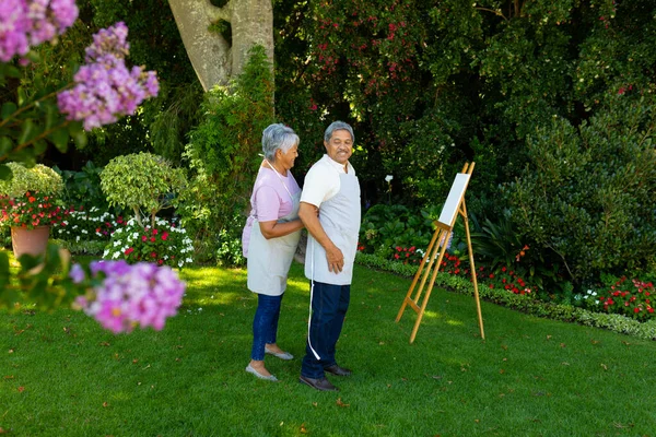 Biracial Senior Woman Tying Husband Apron Standing Canvas Easel Plants — Photo