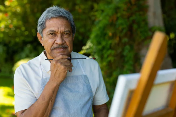 Portrait Biracial Senior Man Holding Paintbrush Hand Chin Standing Plants — Photo