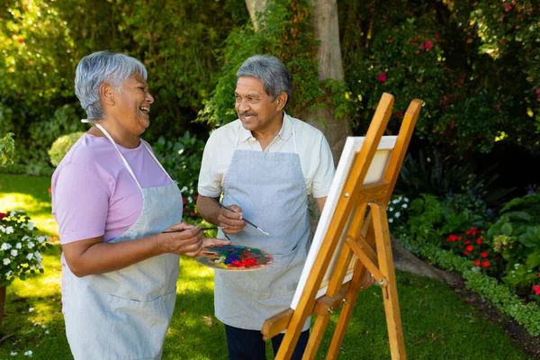 Biracial Senior Man Looking Wife Laughing While Painting Watercolors Canvas — Stok fotoğraf