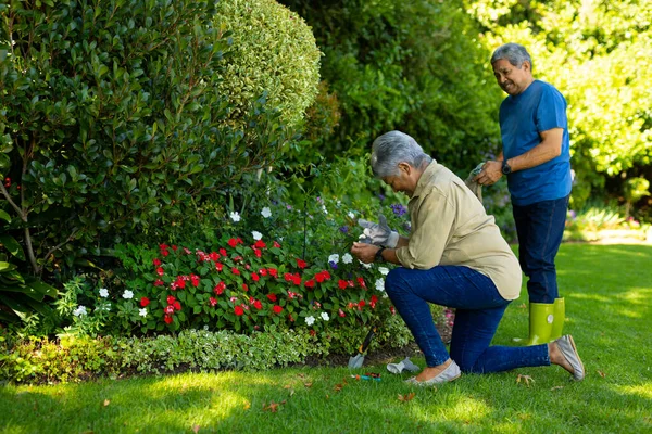 Biracial Senior Woman Husband Wearing Gloves While Gardening Flowers Plants — стоковое фото