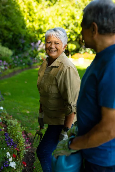 Smiling Biracial Senior Woman Looking Husband Holding Watering Can While — Fotografia de Stock