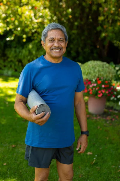 Porträtt Leende Biracial Senior Man Bär Sportkläder Håller Yogamatta Gården — Stockfoto