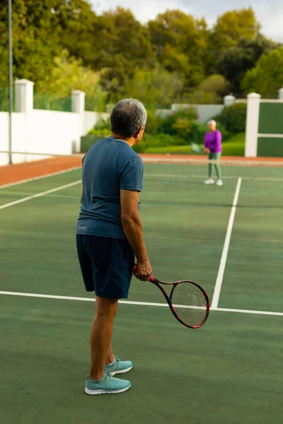 Biracial Senior Man Holding Racket Playing Tennis Senior Wife Trees — Stockfoto