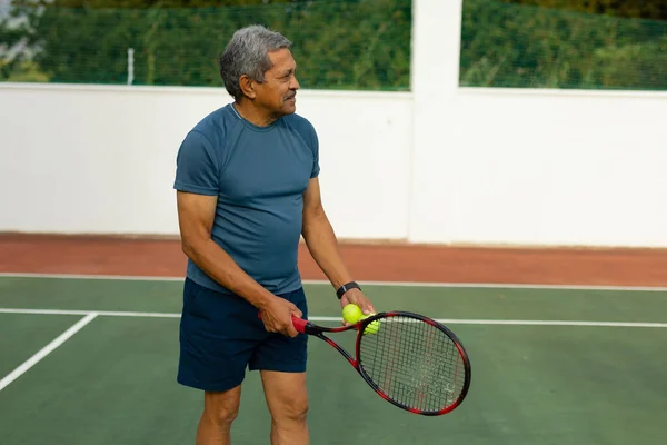 Confident Biracial Senior Man Holding Racket Ball Looking Away While — Foto de Stock