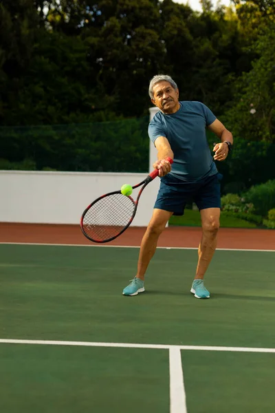 Biracial Senior Man Hitting Tennis Ball Racket While Playing Tennis — Foto de Stock