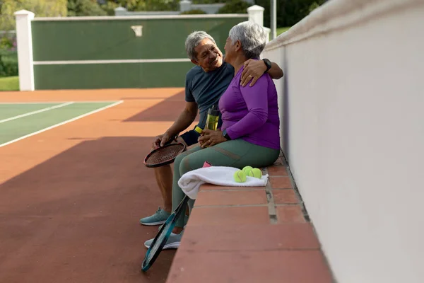 Smiling Biracial Senior Husband Looking Wife While Sitting Bench Tennis — стоковое фото