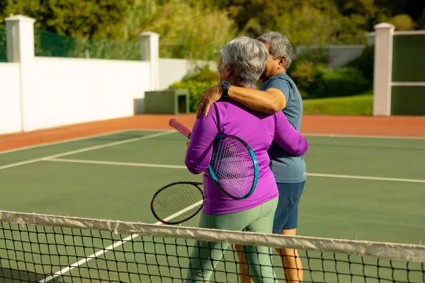 Pareja Mayor Biracial Con Brazos Alrededor Sosteniendo Raquetas Caminando Cancha — Foto de Stock