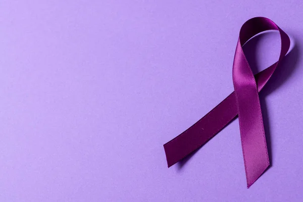 High angle view of purple awareness ribbon isolated against purple background, copy space. epilepsy, pancreatic cancer, medical, awareness, ribbon, support, healthcare and alertness concept.