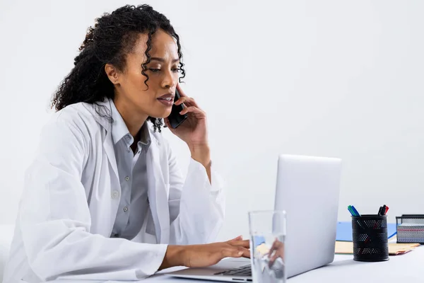 African American Mid Adult Woman Talking Smart Phone Using Laptop — Stockfoto