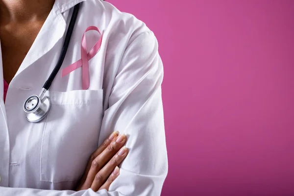 ピンクの乳がんの意識リボンを持つ医師の中央部 コピースペース ピンクの背景医師医療意識支援医療職業 — ストック写真