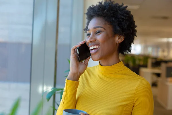 快乐的年轻非洲裔美国女商人一边在办公室拿着咖啡杯一边用智能手机说话 现代办公和无线技术概念 — 图库照片