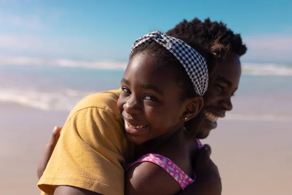 一个微笑的非洲裔美国女孩的近照 她拥抱着年轻的父亲 与大海和天空相映成趣 生活方式 — 图库照片