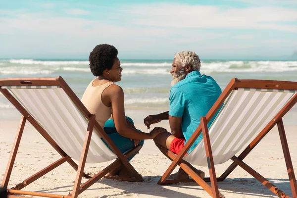African American Couple Talking While Sitting Deckchairs Sandy Beach Cloudy — Stock Photo, Image