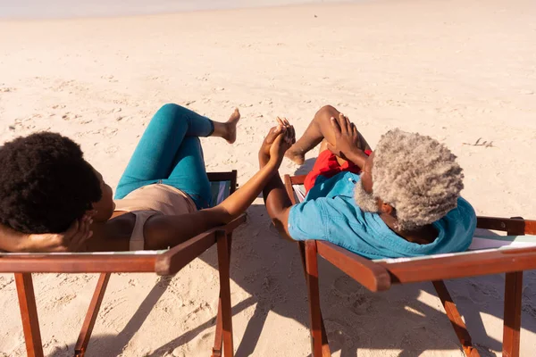 砂浜でデッキチェアに座っている間 アフリカ系アメリカ人のカップルの手を握っているの高い角度のビュー リラックス 変わらない愛 楽しみと休日の概念 — ストック写真