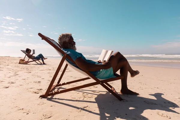 Hombre Mayor Afroamericano Mujer Madura Leyendo Libros Mientras Relaja Tumbonas —  Fotos de Stock