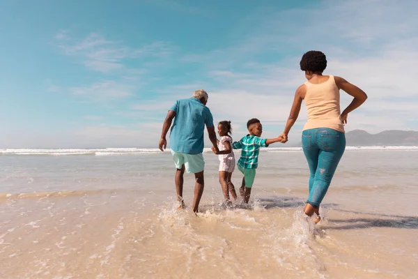 Avós Afro Americanos Segurando Mãos Netos Correndo Mar Contra Céu — Fotografia de Stock